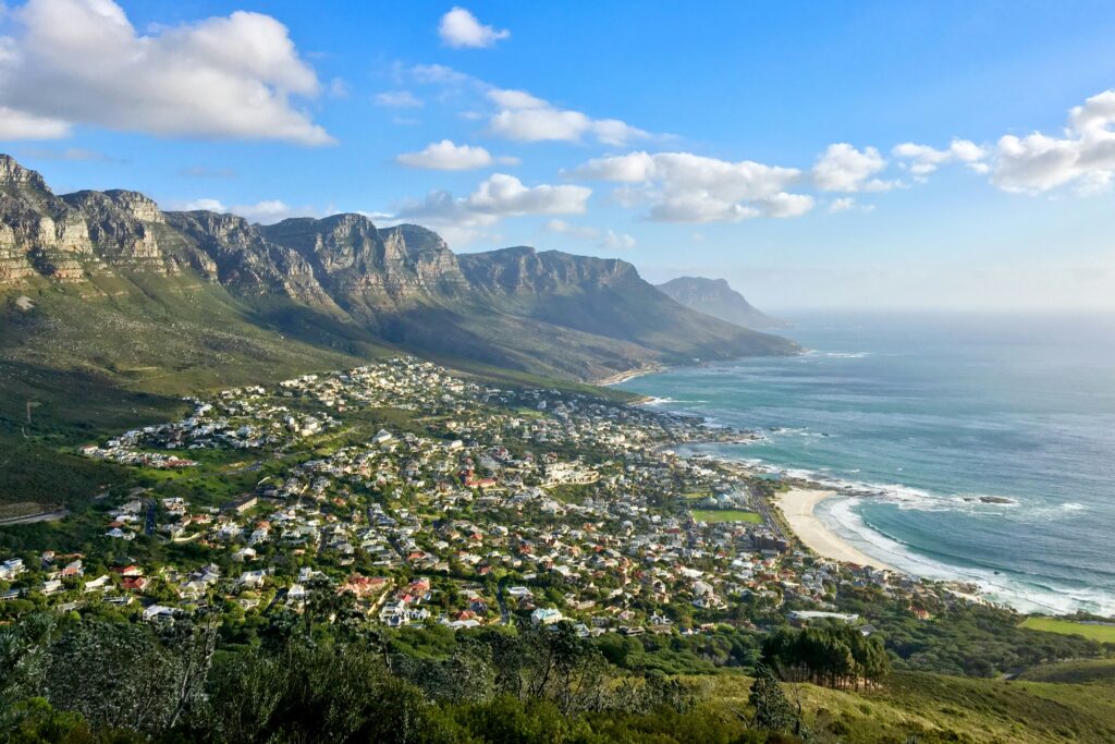 Esta foto panorâmica aérea exibe a magnífica Table Mountain e os Doze Apóstolos abraçando a vibrante Cidade do Cabo e suas praias costeiras, oferecendo uma vista espetacular que é um dos maiores cartões-postais da África do Sul.