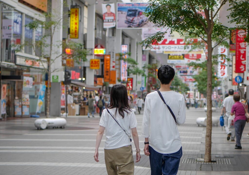 Casal ou amigos caminhando em uma rua de pedestres com prédios e letreiros japoneses.