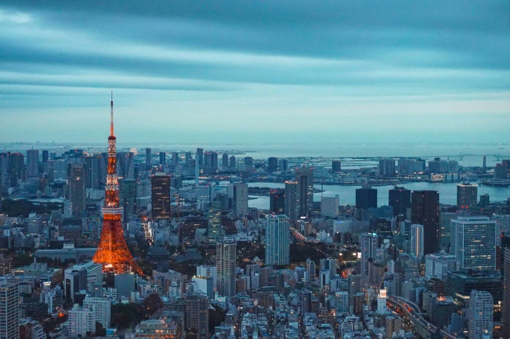 Vista panorâmica da cidade de Tóquio, Japão, ao anoitecer, com a Torre de Tóquio laranja e branca se destacando entre os inúmeros edifícios da metrópole.