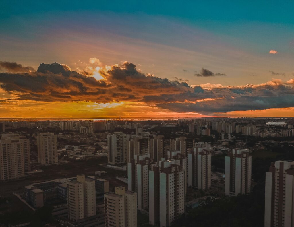 A beleza urbana de Manaus se revela em um espetacular pôr do sol amazônico.
Visão aérea do horizonte de Manaus ao entardecer, com a silhueta dos prédios residenciais iluminada por um céu vibrante em tons de laranja e azul.